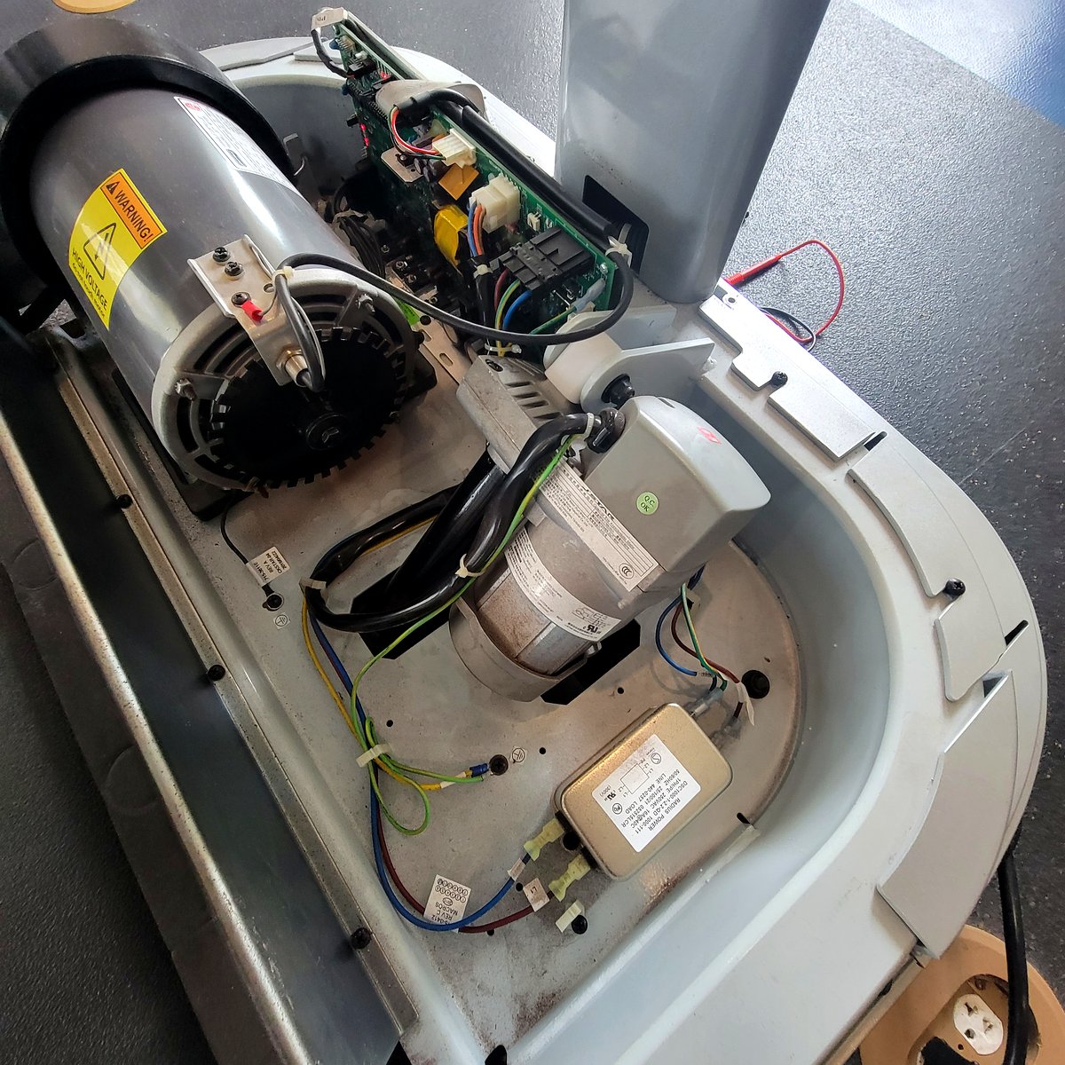 Fitness equipment opened up for diagnosis showing motor and circuit board